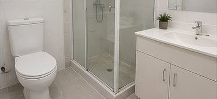 The same bathroom after cleaning, gleaming white tiles and fittings