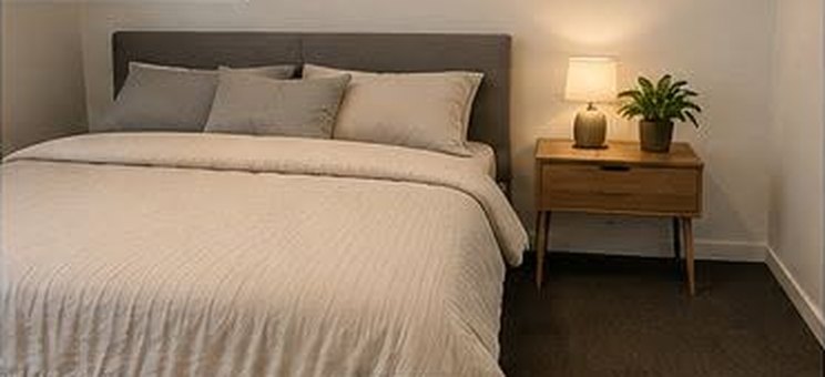 The same bedroom after cleaning, neatly made bed and clear floor