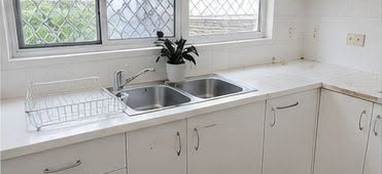 The same kitchen after cleaning, spotless white cabinets and sink