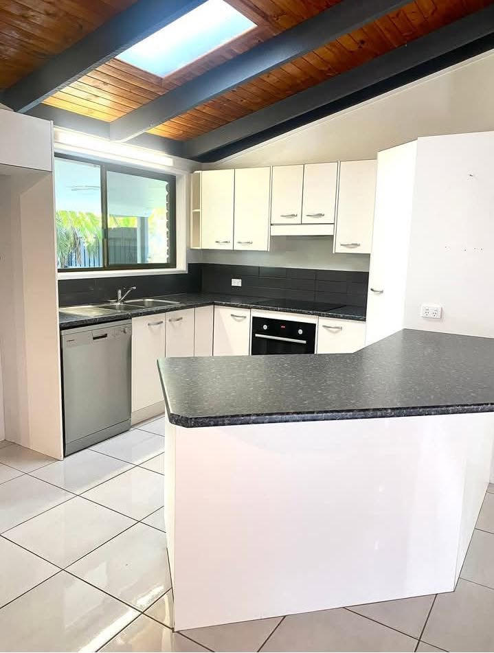 A freshly cleaned white kitchen with gleaming tiled floor and clean benchtops